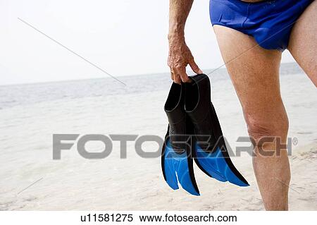 Stock Photography - Senior man with flippers at the beach . Fotosearch