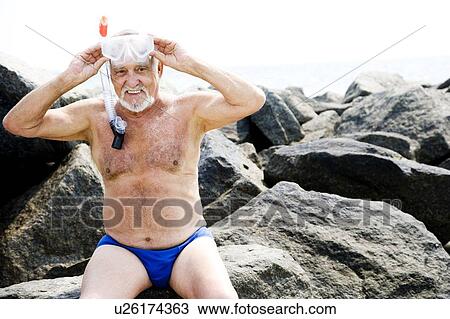 Stock Image - Senior man with snorkel gear at the beach . Fotosearch
