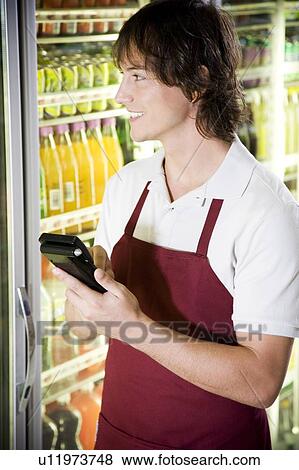 Stock Photo - Shop assistant stocktaking in a supermarket. Fotosearch
