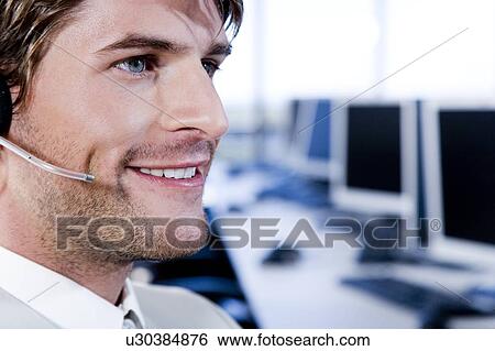 Stock Photograph - Smiling businessman in a call centre. Fotosearch