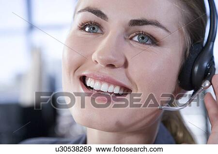Stock Photo - Smiling businesswoman wearing a call centre headset. Fotosearch