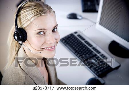 Stock Photo - Smiling woman wearing a call centre headset. Fotosearch