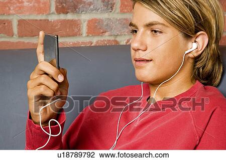 Teenage boy on a seat listening to music on mp3 View Large Photo Image Stock Image - Teenage boy on a seat listening to music on mp3. Fotosearch