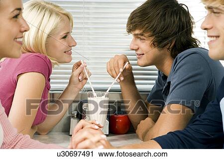 Stock Image - Teenage couple sharing a milkshake . Fotosearch