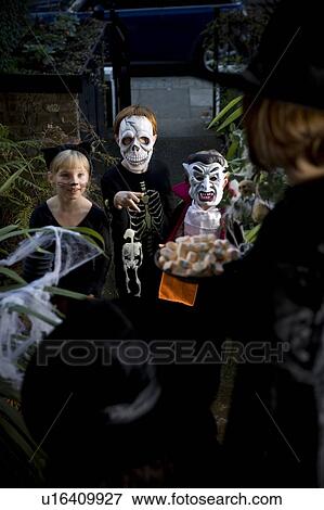 Stock Photo - Three friends Trick or Treating at Halloween. Fotosearch