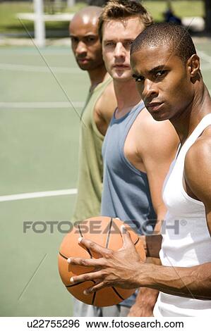 Stock Photograph - Three men standing on an outdoor basketball court . Fotosearch