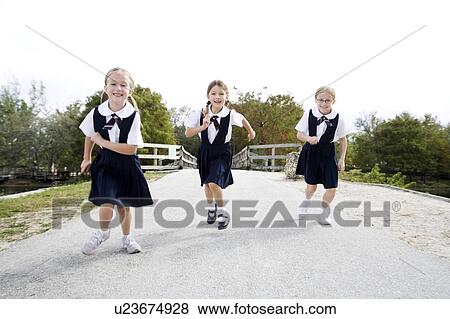 Stock Photo - Three schoolgirls running down a road. Fotosearch