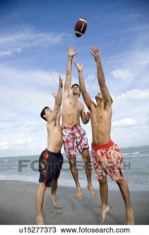 Three young men playing with a ball on a beach View Large Photo Image Stock Image - Three young men playing with a ball on a beach. Fotosearch