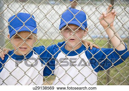 Stock Photo - two boys hugging looking through fence. Fotosearch