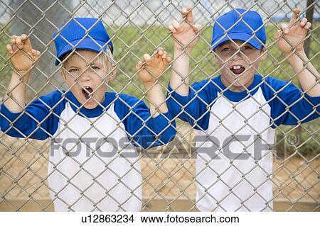 two boys roaring like lions through fence at baseball pitch View Large Photo Image Picture - two boys roaring like lions through fence at baseball pitch. Fotosearch