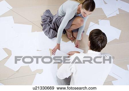 Stock Photo - Two business colleagues picking up dropped files and paperwork from the floor. Fotosearch