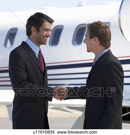 Stock Photography - Two business colleagues shaking hands before departure. Fotosearch