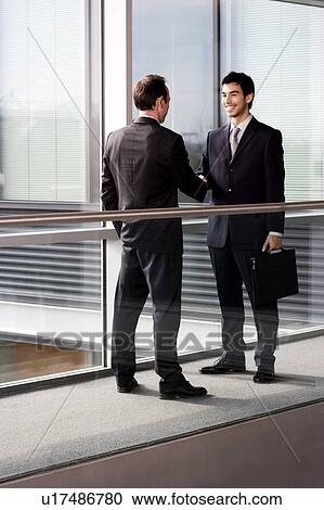 Stock Image - Two businessmen shaking hands. Fotosearch