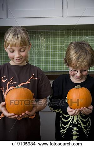 Picture - Two children holding orange Hallowe'en pumpkins. Fotosearch