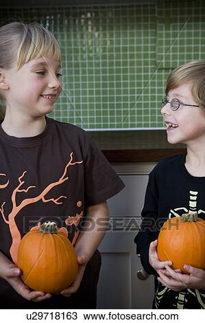 Stock Image - Two children holding orange Hallowe'en pumpkins. Fotosearch