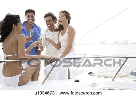 Stock Image - Two couples having drinks on board a luxury yacht. Fotosearch