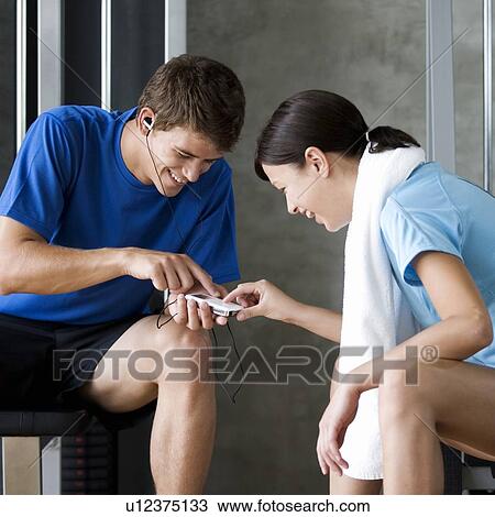 Two friends listening to music in a gym View Large Photo Image Stock Image - Two friends listening to music in a gym. Fotosearch