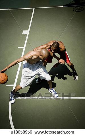 Stock Photograph - Two men playing on an outdoor basketball court . Fotosearch