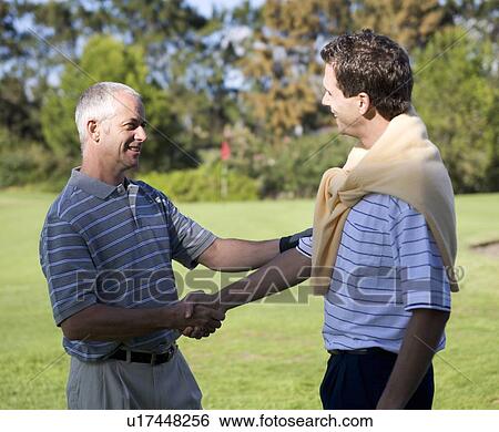 Stock Photograph - Two men shaking hands on a golf course. Fotosearch