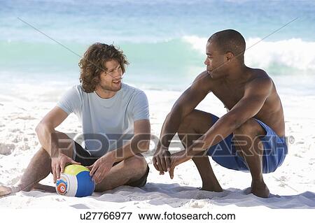 Two men sitting on a beach View Large Photo Image Stock Photo - Two men sitting on a beach. Fotosearch