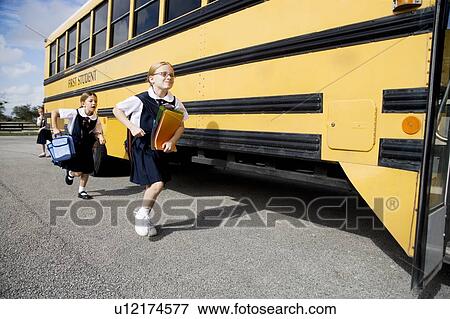 Stock Photo - Two schoolgirls running for the school bus. Fotosearch