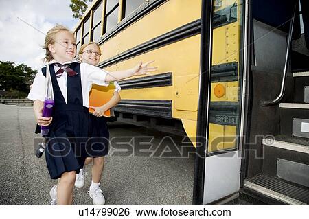 Stock Photograph - Two schoolgirls running for the school bus. Fotosearch