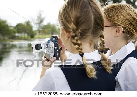 Stock Photography - Two schoolgirls using a video camera. Fotosearch