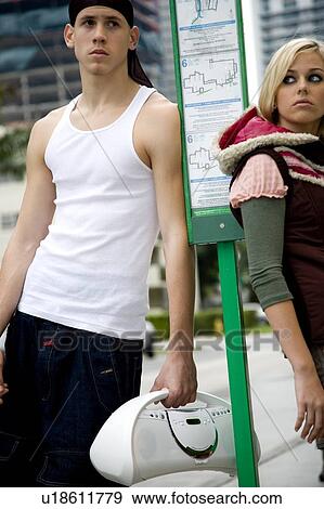 Stock Photo - Two teenagers standing at a bus stop. Fotosearch