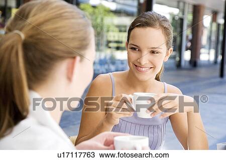 Stock Image - Two women drinking coffee at a pavement cafe. Fotosearch