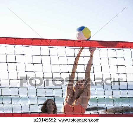 Stock Image - Two women playing beach volleyball. Fotosearch