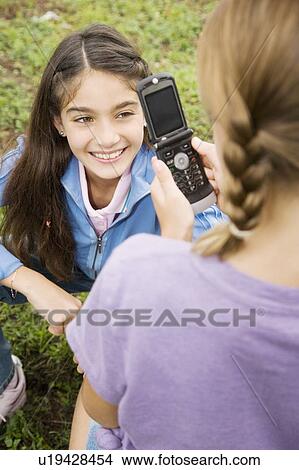 Two young friends taking pictures with their mobile phone View Large Photo Image Picture - Two young friends taking pictures with their mobile phone. Fotosearch