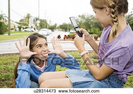 Two young friends taking pictures with their mobile phone View Large Photo Image Stock Image - Two young friends taking pictures with their mobile phone. Fotosearch