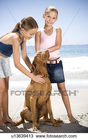 Stock Image - Two young girls and a dog on the beach. Fotosearch