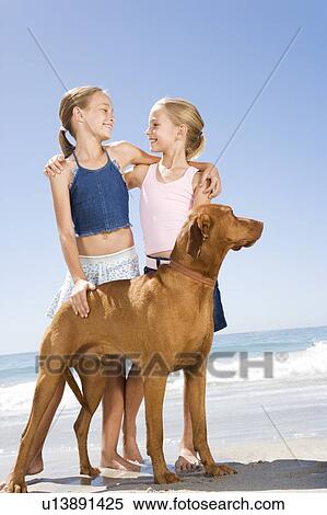 Two young girls and a dog on the beach View Large Photo Image Stock Photography - Two young girls and a dog on the beach. Fotosearch