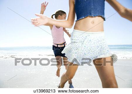 Stock Image - Two young girls having fun on the beach. Fotosearch