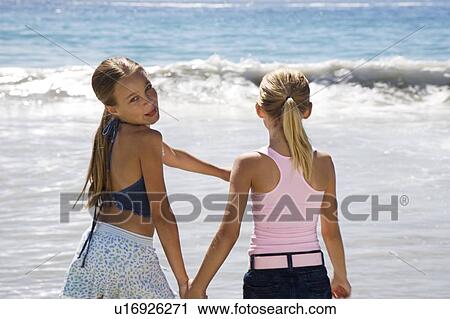 Two young girls holding hands on the beach View Large Photo Image Stock Image - Two young girls holding hands on the beach. Fotosearch