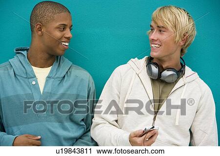Stock Image - Two young men leaning against a green painted wall . Fotosearch