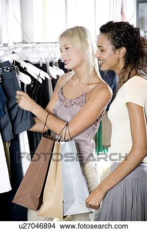 Two young women shopping for clothes View Large Photo Image Picture - Two young women shopping for clothes. Fotosearch