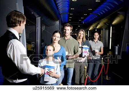 Stock Photo - Usher with queue of people at the cinema. Fotosearch