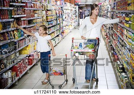 Woman and a young girl with a shopping trolley walking down a supermarket aisle View Large Photo Image Stock Image - Woman and a young girl with a shopping trolley walking down a supermarket aisle. Fotosearch