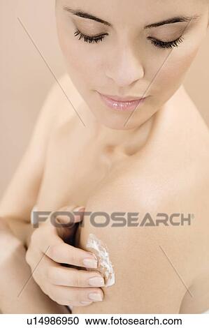 Stock Image - Woman applying moisturising cream. Fotosearch