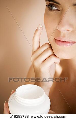 Stock Photo - Woman applying moisturising cream to her face. Fotosearch