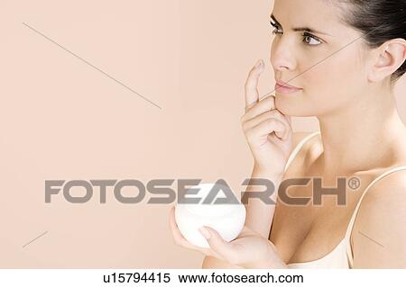 Stock Photography - Woman applying moisturising cream to her face. Fotosearch