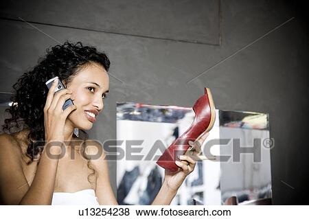 Woman buying high-heeled shoes in a shoe shop, talking on mobile phone View Large Photo Image Stock Photo - Woman buying high-heeled shoes in a shoe shop, talking on mobile phone. Fotosearch