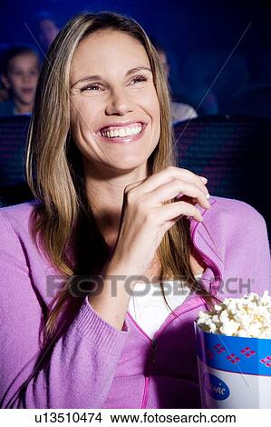 Picture - Woman enjoying a film at the cinema. Fotosearch