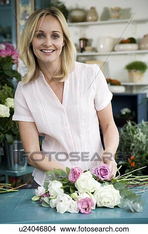 Picture - Woman florist creating a bouquet of pink and white roses. Fotosearch