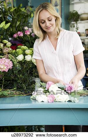 Stock Image - Woman florist creating a bouquet of pink and white roses. Fotosearch