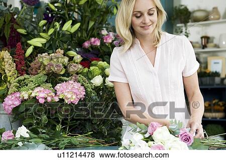 Stock Photo - Woman florist creating a bouquet of pink and white roses. Fotosearch