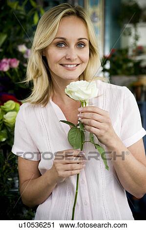 Woman florist in her shop, holding a white rose View Large Photo Image Stock Image - Woman florist in her shop, holding a white rose. Fotosearch