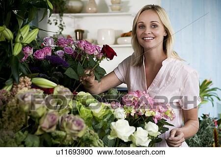 Stock Image - Woman florist in her shop, surrounded by an assortment of flowers. Fotosearch